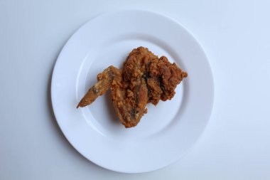 Bir kanatlı kızarmış tavuk, beyaz tabakta, beyaz arka planda izole, düz ya da üst görünümde.