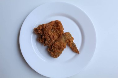 Bir kanatlı kızarmış tavuk, beyaz tabakta, beyaz arka planda izole, düz ya da üst görünümde.