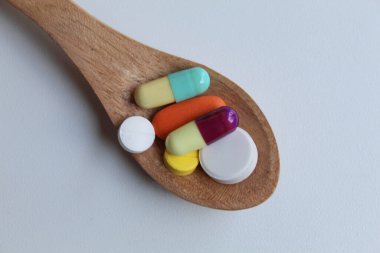 Some medicines on wooden spoon. Isolated on white background, flat lay or top view clipart