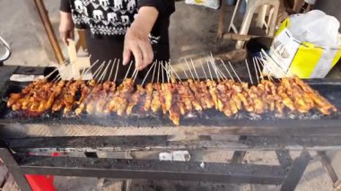 Geleneksel kömür ızgarasının yanında tavuk pişirmek. Endonezyalı sokak yemekleri satıcısı