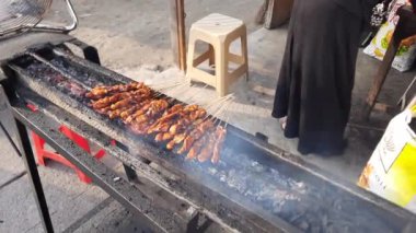 Geleneksel kömür ızgarasının yanında tavuk pişirmek. Endonezyalı sokak yemekleri satıcısı