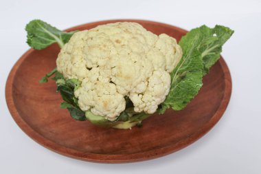 Beyaz arka planda izole edilmiş, ahşap bir tabakta beyaz bir karnabahar.