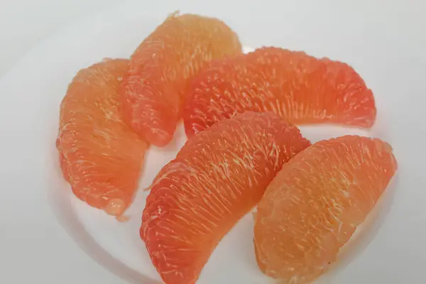 Taze soyulmuş nar meyvesi, beyaz tabakta, beyaz arka planda izole edilmiş.