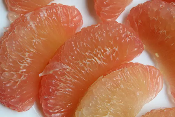 Beyaz arkaplanda, soyulmuş pomelo meyvesinin yakın görünümü