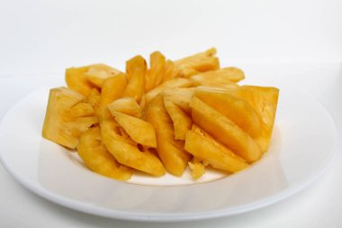 Ananas etini beyaz tabakta kes, beyaz arka planda izole et.