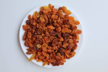 Beyaz bir tabakta kuru üzüm yığını, beyaz arkaplanda izole, düz ya da üst görünümde