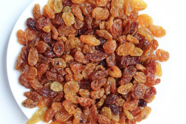 Beyaz bir tabakta kuru üzüm yığını, beyaz arkaplanda izole, düz ya da üst görünümde