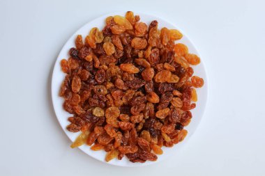 Beyaz bir tabakta kuru üzüm yığını, beyaz arkaplanda izole, düz ya da üst görünümde