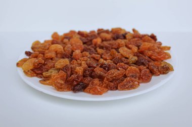 Beyaz bir tabakta beyaz arka planda izole edilmiş kuru üzüm yığını.