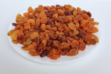 Beyaz bir tabakta beyaz arka planda izole edilmiş kuru üzüm yığını.