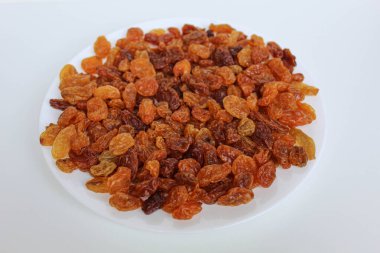 Beyaz bir tabakta beyaz arka planda izole edilmiş kuru üzüm yığını.