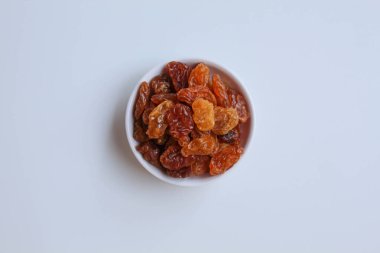 Beyaz zemin üzerinde izole edilmiş, küçük beyaz bir kasede kuru üzüm yığını.