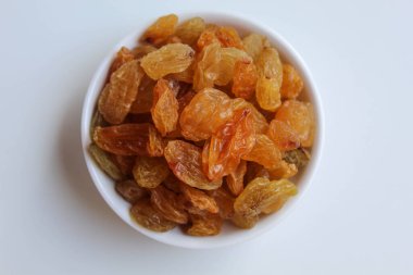 Kuru üzümler küçük beyaz bir kasede, beyaz zemin üzerinde izole, düz ya da üst görünüm