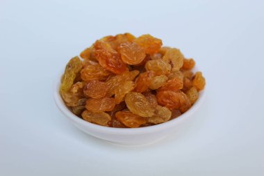 Beyaz arka planda izole edilmiş küçük beyaz bir kasede kuru üzümler.