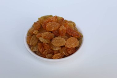 Beyaz arka planda izole edilmiş küçük beyaz bir kasede kuru üzümler.