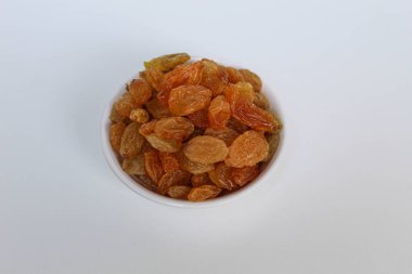 Beyaz arka planda izole edilmiş küçük beyaz bir kasede kuru üzümler.