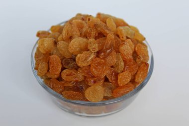 Şeffaf bir kasede sarı kuru üzümler, beyaz arka planda izole edilmiş.