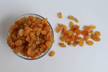 Şeffaf bir kaseden taşan kuru üzümler, dağınık, izole beyaz arka plan