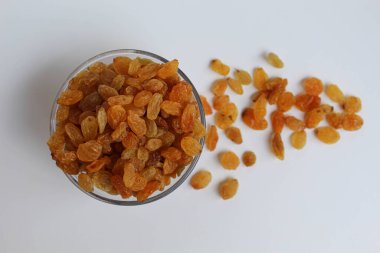 Şeffaf bir kaseden taşan kuru üzümler, dağınık, izole beyaz arka plan