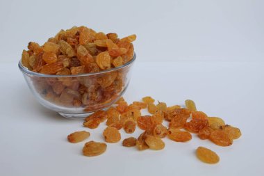 Şeffaf bir kaseden taşan kuru üzümler, dağınık, izole beyaz arka plan