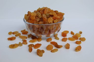 Şeffaf bir kaseden taşan kuru üzümler, dağınık, izole beyaz arka plan