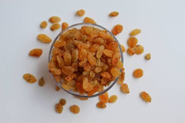 Şeffaf bir kaseden taşan kuru üzümler, dağınık, izole beyaz arka plan