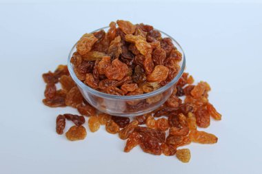 Şeffaf bir kaseden taşan kuru üzümler, dağınık, izole beyaz arka plan