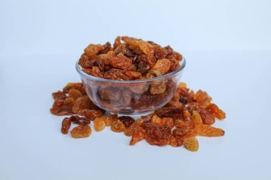 Şeffaf bir kaseden taşan kuru üzümler, dağınık, izole beyaz arka plan