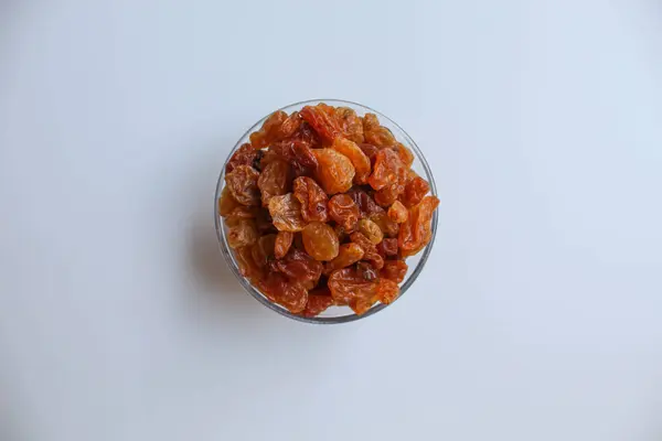 Şeffaf bir kâse içinde kuru üzüm yığını, beyaz arka planda izole, düz ya da üst görünüm