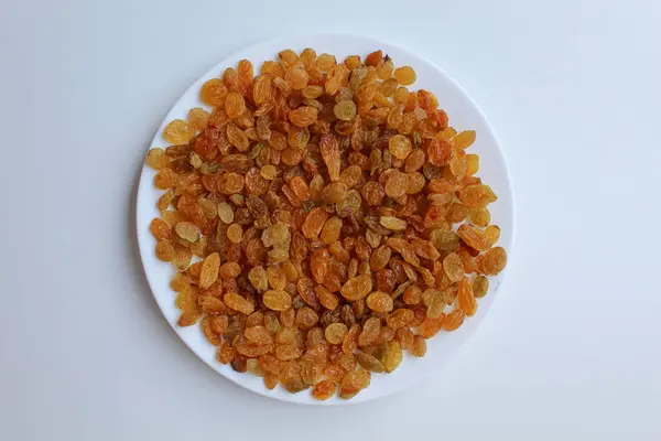 Beyaz bir tabakta kuru üzüm yığını, beyaz arkaplanda izole, düz ya da üst görünümde