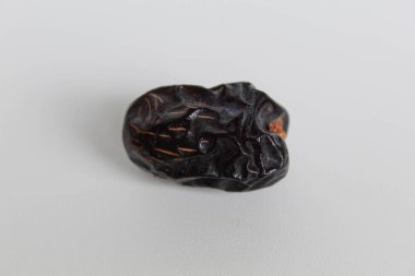 Bir parça ajwa tarihi ya da ajwa khajur, beyaz arka planda izole edilmiş.