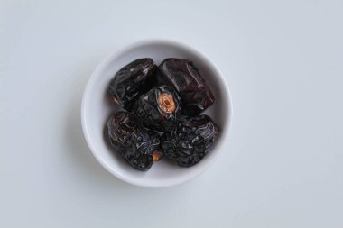 Beş parça ajwa hurması ya da ajwa khajur, küçük kasede, beyaz arka planda izole, düz ya da üst görünümde