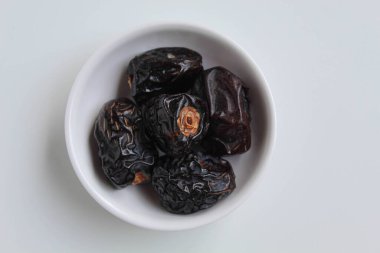 Beş parça ajwa hurması ya da ajwa khajur, küçük kasede, beyaz arka planda izole, düz ya da üst görünümde