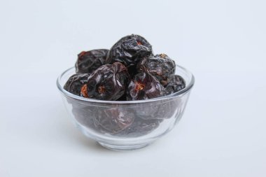 Ajwa tarihleri ya da ajwa hajur, şeffaf kâsede, beyaz arka planda izole edilmiş.