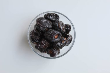 Ajwa tarihleri ya da ajwa hajur, şeffaf kâsede, beyaz arka planda izole edilmiş, düz ya da üst görünümde