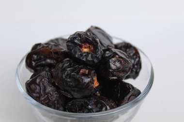 Ajwa tarihleri ya da ajwa hajur, şeffaf kâsede, beyaz arka planda izole edilmiş.