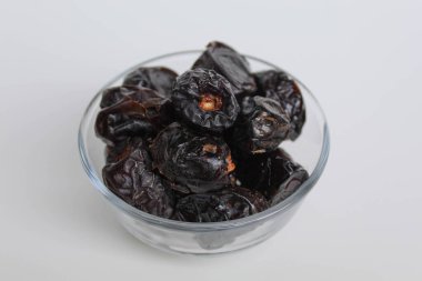 Ajwa tarihleri ya da ajwa hajur, şeffaf kâsede, beyaz arka planda izole edilmiş.