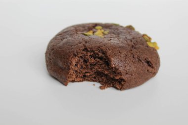 Isırılmış çikolatalı yumuşak kurabiye, yeşil fıstıklı, beyaz arka planda izole edilmiş.