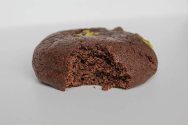 Isırılmış çikolatalı yumuşak kurabiye, yeşil fıstıklı, beyaz arka planda izole edilmiş.