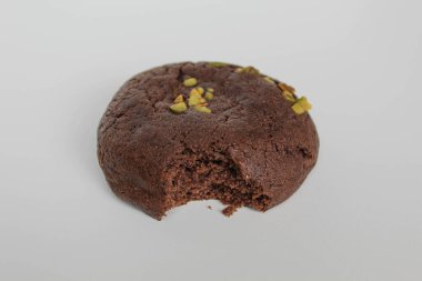 Isırılmış çikolatalı yumuşak kurabiye, yeşil fıstıklı, beyaz arka planda izole edilmiş.