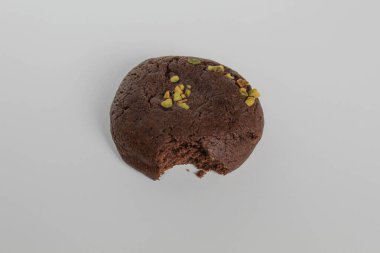 Isırılmış çikolatalı yumuşak kurabiye, yeşil fıstıklı, beyaz arka planda izole edilmiş.