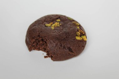 Isırılmış çikolatalı yumuşak kurabiye, yeşil fıstıklı, beyaz arka planda izole edilmiş.