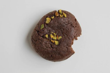 Isırılmış çikolatalı yumuşak kurabiye, yeşil fıstıklı, beyaz arka planda izole edilmiş, düz ya da üst manzaralı.