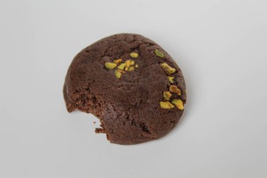 Isırılmış çikolatalı yumuşak kurabiye, yeşil fıstıklı, beyaz arka planda izole edilmiş.