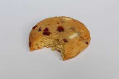 Beyaz arka planda izole edilmiş badem ve böğürtlen kesikli ısırılmış beyaz çikolatalı kurabiye.