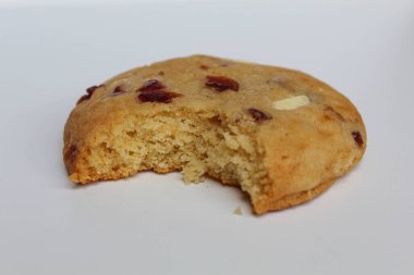 Beyaz arka planda izole edilmiş badem ve böğürtlen kesikli ısırılmış beyaz çikolatalı kurabiye.