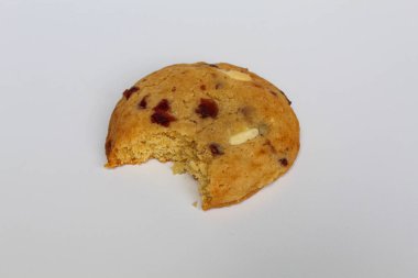 Beyaz arka planda izole edilmiş badem ve böğürtlen kesikli ısırılmış beyaz çikolatalı kurabiye.