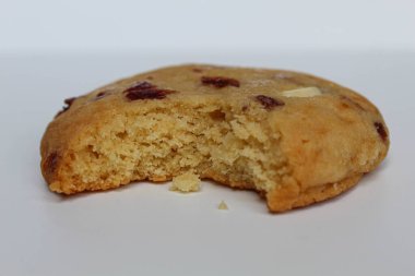 Beyaz arka planda izole edilmiş badem ve böğürtlen kesikli ısırılmış beyaz çikolatalı kurabiye.