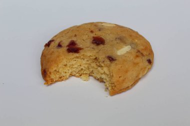 Beyaz arka planda izole edilmiş badem ve böğürtlen kesikli ısırılmış beyaz çikolatalı kurabiye.