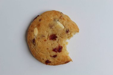 Beyaz arka planda izole edilmiş badem ve böğürtlen kesikli ısırılmış beyaz çikolatalı kurabiye.